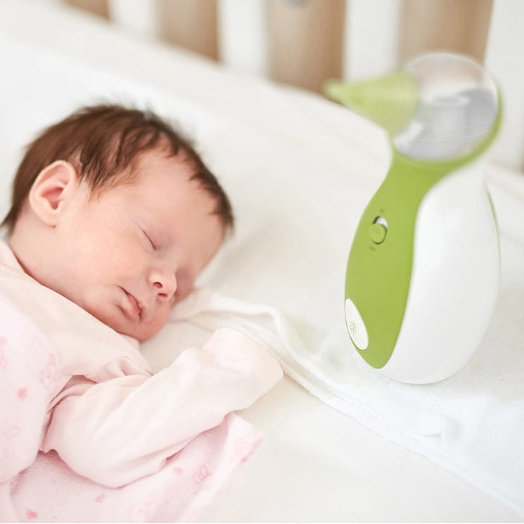 Un bébé dormant paisiblement dans le lit pour bébé à côté d'un mouche-bébé portatif Nosiboo Go