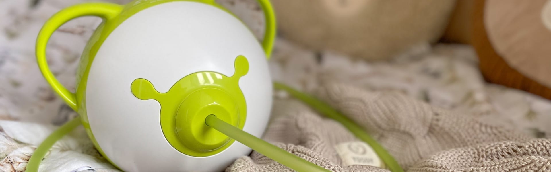 Un mouche-bébé électrique Nosiboo Pro2 vert sur un lit.