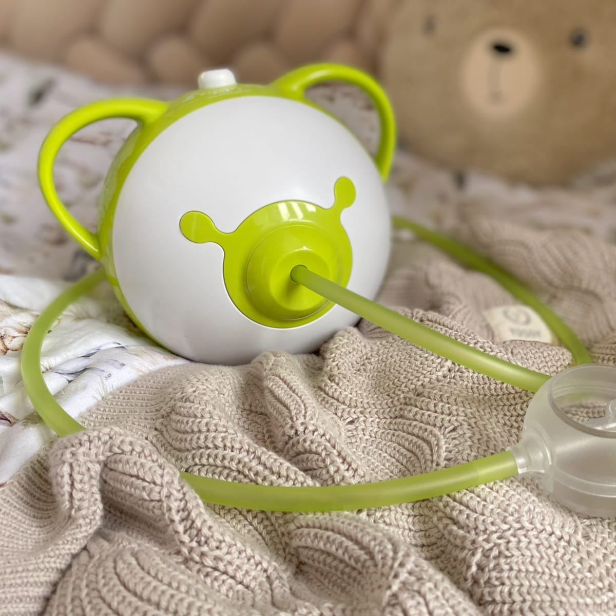 Un mouche-bébé électrique Nosiboo Pro2 vert sur un lit.