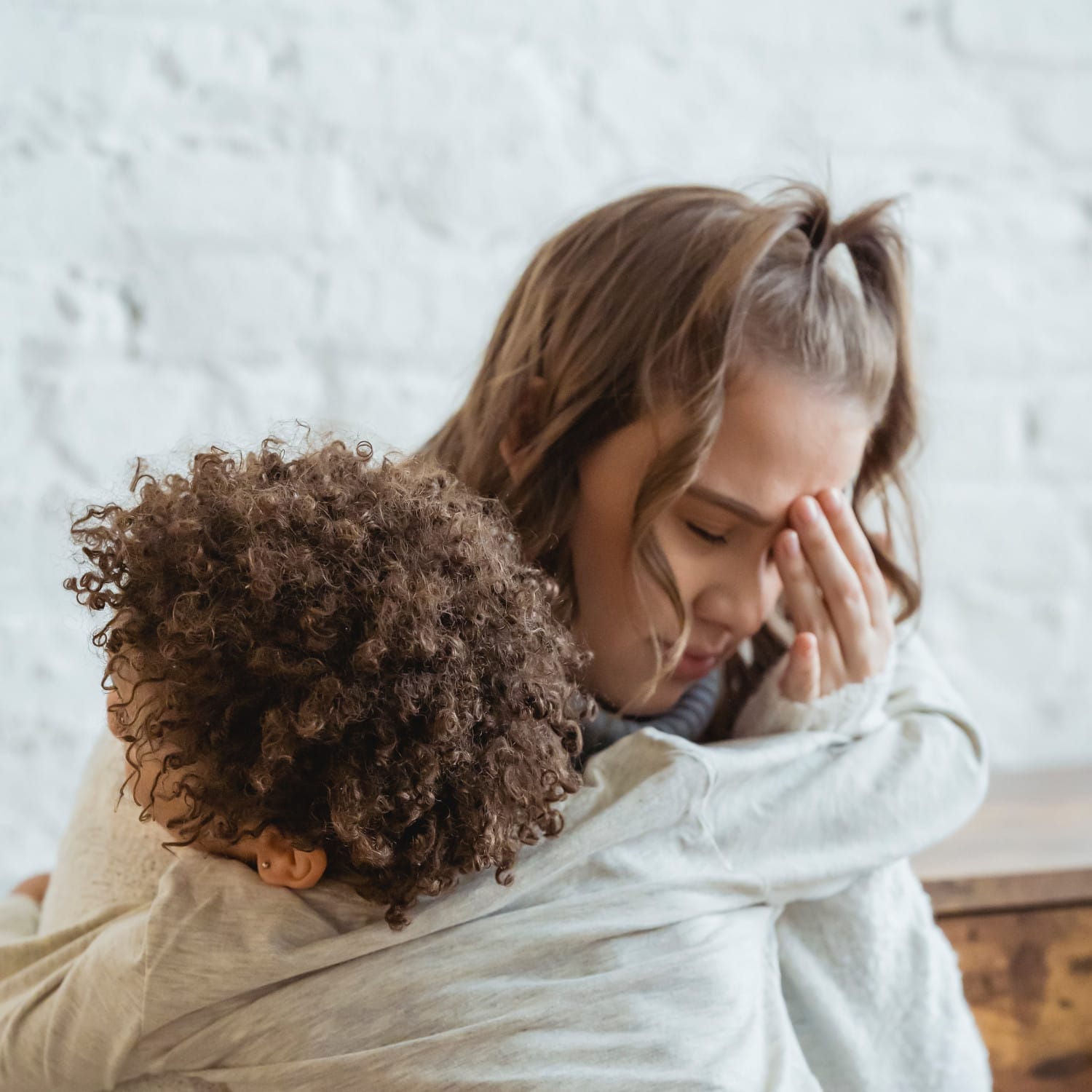 Une femme inquiète se tient la tête en serrant son enfant dans ses bras.