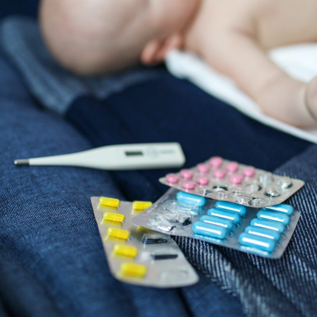 Des médicaments et un thermomètre sur le lit